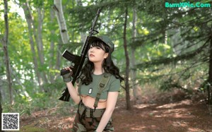 A woman in a military uniform standing on a path in the woods.