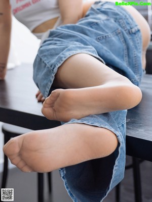 A woman sitting on top of a table with her legs crossed.