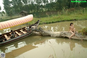 A naked woman sitting on a wooden ladder in front of a hut.