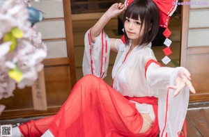 A woman in a red and white outfit sitting on a bench.