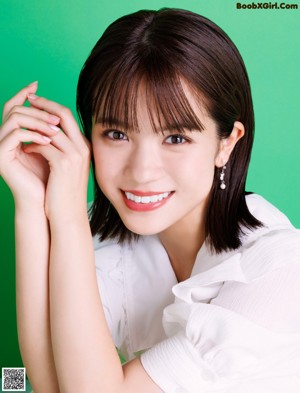 A woman in a white dress sitting on a green background.