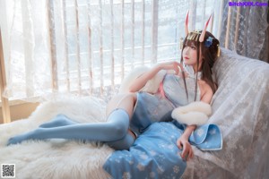 A woman in a white fur coat with horns on her head.