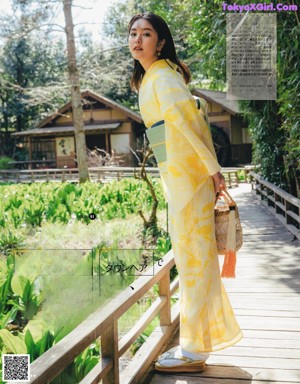 A woman in a kimono leaning on a railing.