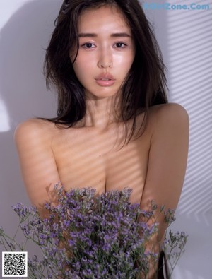 A woman in a white lingerie leaning against a wall.