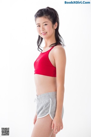 A young woman in a red top and gray shorts.