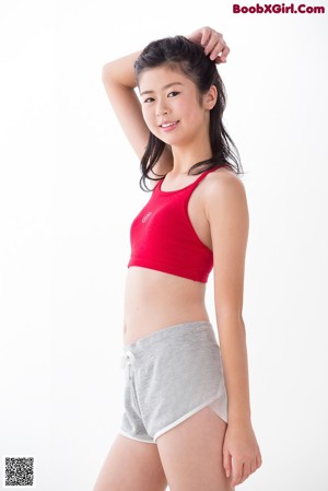 A woman in a red top and gray shorts posing for a picture.