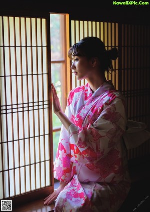 A woman in a blue and pink kimono posing for a picture.