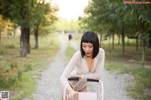 A woman in a white bodysuit and high heels standing next to a pink cart.