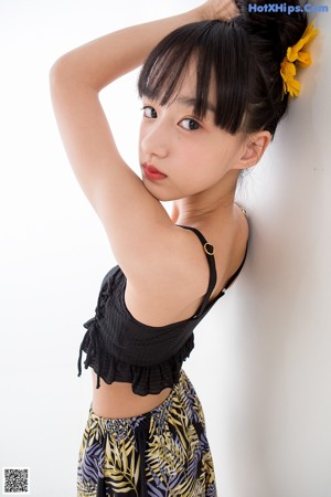A woman in a black top and yellow shorts posing for a picture.