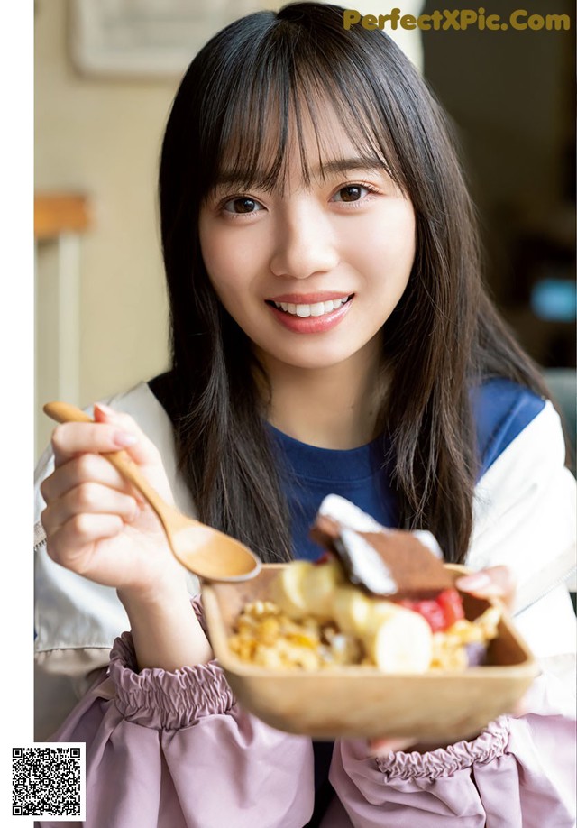 A young woman holding a bowl of food with a spoon.