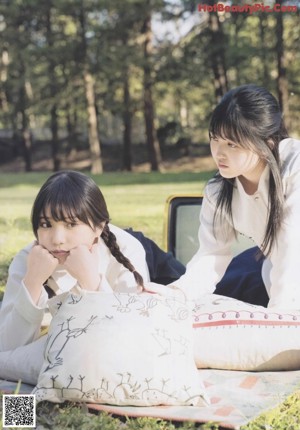 A couple of women sitting next to each other in a field.