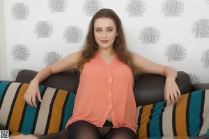 A woman sitting on top of a bed in a black top.