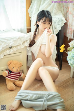 A young woman sitting on the floor holding a stuffed animal.