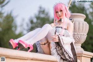 A woman with pink hair sitting on a white couch.
