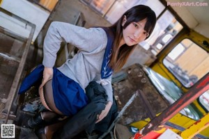 A woman in a school uniform crouching on a train track.