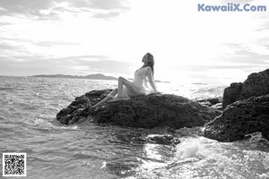 A woman in a bikini sitting on the edge of a pool.