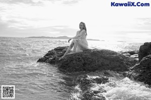 A woman sitting on a wooden bench on the beach.