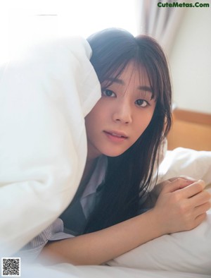 A woman in a white dress sitting on a bed.