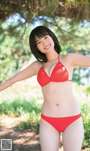 A woman in a red bikini standing on a beach.