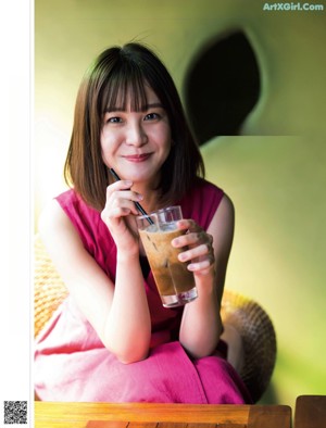 A woman sitting at a table with a drink in her hand.