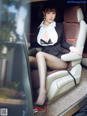 A woman in a business suit is getting out of a car.