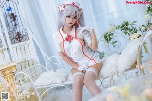 A woman dressed as a nurse sitting on a white chair.