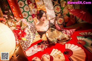 A woman in a kimono holding a red umbrella.