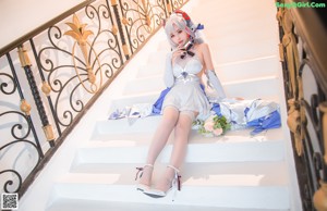 A woman in a white and blue outfit holding a bouquet of flowers.
