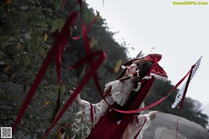 A woman in a red and white dress laying on a rock.
