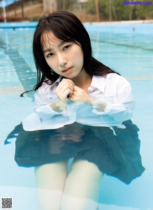 A woman in a white bikini leaning against a fence.