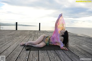 A naked asian woman leaning against a window.
