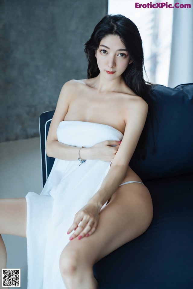 A woman in a white towel sitting on a blue couch.