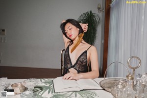 A woman in a black lingerie sitting on a bed.