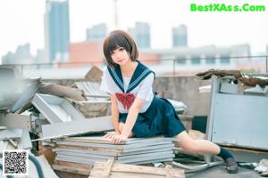 A woman in a school uniform sitting on a pile of rubble.