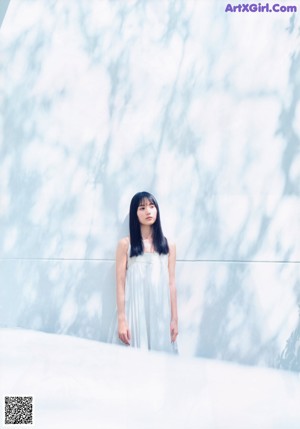 A woman with long black hair standing by the water.