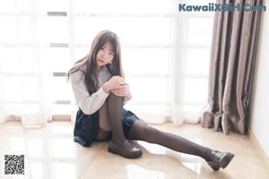 A woman in black stockings and a skirt is standing on the floor.