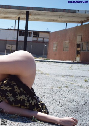 A woman laying on the ground in a black and gold dress.