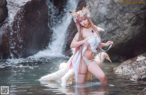 A woman in a white dress standing in the water with a fox.